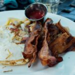 Close-up of a breakfast plate with fried eggs, bacon, and sauce, ready to enjoy.