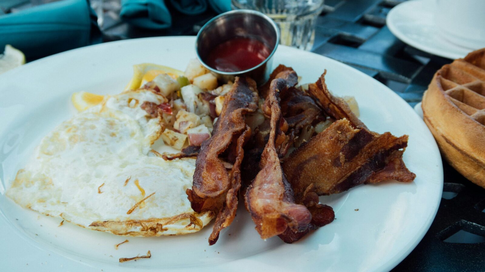Close-up of a breakfast plate with fried eggs, bacon, and sauce, ready to enjoy.