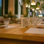 a wooden table topped with glasses and a vase filled with flowers